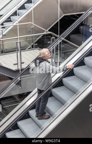 A Middle aged man riding an escalator alone Stock Photo