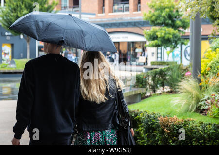 A couple walking together under an umbrella in heavy rain Stock Photo