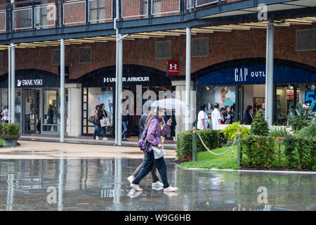 Two women taking shelter from the rain under one umbrella