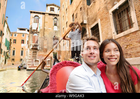 Romantic travel couple in Venice on Gondola ride romance in boat talking happy together on travel vacation holidays. Young multiracial couple sailing in venetian canal in gondole. Italy, Europe Stock Photo