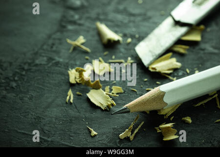 White pencil and cutter on black cement floor. Copy space for text. Concept of education or student equipment. Stock Photo