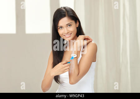 Young woman shaving her forearm Stock Photo