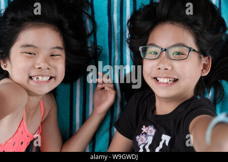 Two sisters laying down taking selfie photo Stock Photo