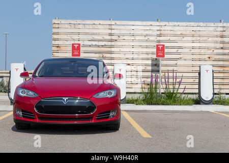 Front of 2014 Red Tesla Model S while charging at Tesla Urban Supercharger. Stock Photo