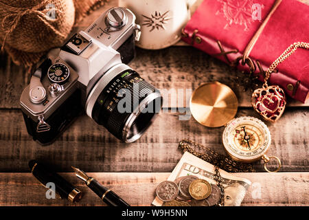 vintage items, pen red book, coins money, compass and retro photo film camera on wood background. Stock Photo