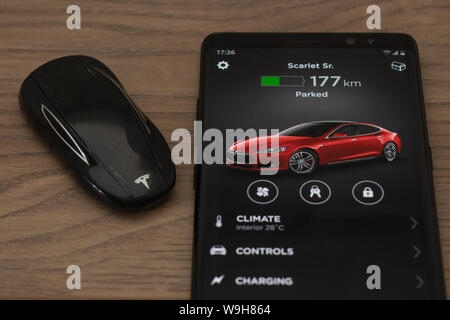 Tesla Model S key fob and Tesla car control app home screen on a smartphone. Stock Photo