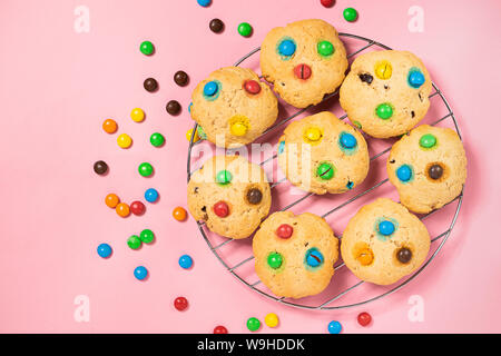 Homemade cookies decorated with colorful jelly beans candies on pink background. Top view flat layout. Holiday concept. Stock Photo