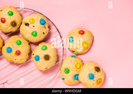 Homemade cookies decorated with colorful jelly beans candies on pink background. Top view flat layout. Holiday concept. Stock Photo
