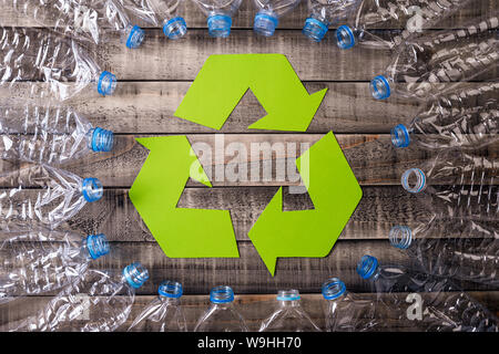 Frame of used plastic bottles with recycling symbol on wooden background. Recycle concept