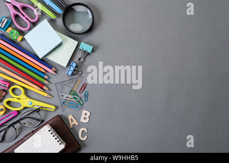 Education or back to school Concept. Top view of Colorful school supplies with books, color pencils, calculator, pen cutter clips and green apple on g Stock Photo
