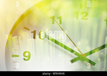 Times clock face overlay with green grass nature background. time to saving environment ecology concept Stock Photo