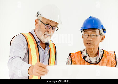two senior professional architecture engineer consulting with builder foreman for safety and fast building home in construction site looking at blueprint Stock Photo