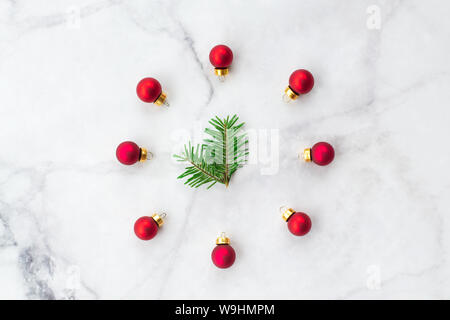 Stylized Christmas clock made of fir-tree branch and red ball toys on marble background. New Year and Christmas celebration concept. Flat lay, top vie Stock Photo