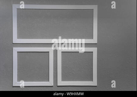 Close-up of three white picture frames on grey wall background Stock Photo