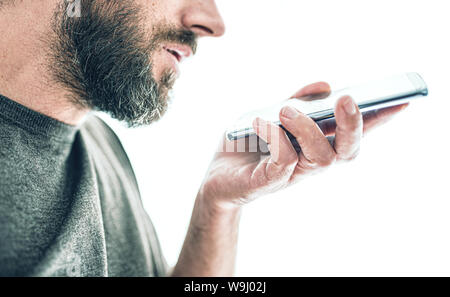 close-up of bearded caucasian man recording voice message or using voice assistant on mobile phone Stock Photo