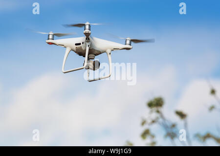 Professional drone quad copter DJI Phantom 4 Pro with digital camera flight in blue sky and photographs world around it from bird's eye view Stock Photo