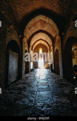 Vertical shot of a arches type hallway with the door in the distance Stock Photo