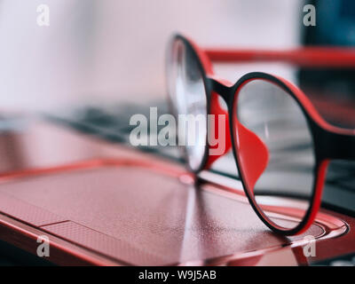 Red eye glasses are placed on the notebook computer in the office at work, Red eye Stock Photo
