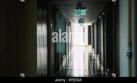 Walkway to the fire escape door, Fire exit sign over corridor walkway in apartment building, Exit signs for emergency along the way in an office Stock Photo