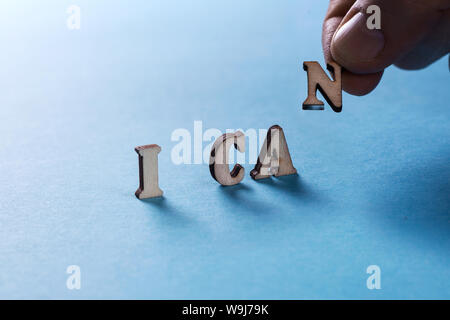 I CAN from wooden letters on a blue background, a man's hand holds a letter Stock Photo