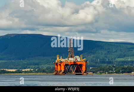 ORANGE OIL RIG OR PLATFORM UNDERGOING REPAIR OR DECOMMISSIONING CROMARTY FIRTH SCOTLAND IN SUMMER Stock Photo