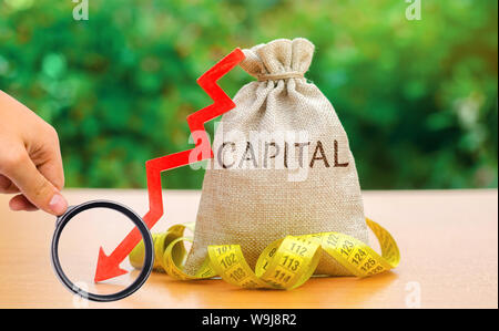 Money bag with the word Capital and arrow down. Fall in the level of authorized capital. Drop in return on equity. The export of fund abroad in order Stock Photo