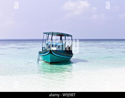 Ari Atoll, Maldives - 25 December 2018: A maldivian sailor is fishing on his blue boat called 'dhoni' Stock Photo