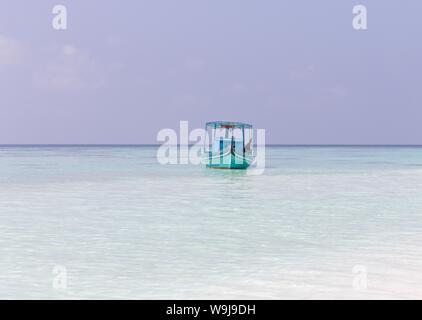 Ari Atoll, Maldives - 25 December 2018: A maldivian sailor is fishing on his blue boat called 'dhoni' Stock Photo