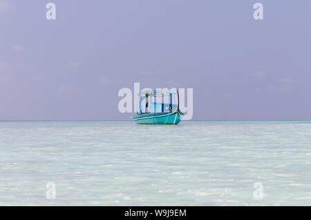 Ari Atoll, Maldives - 25 December 2018: A maldivian sailor is fishing on his blue boat called 'dhoni' Stock Photo