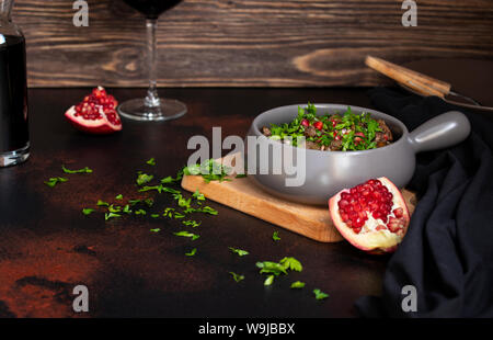 A traditional dish of Georgian cuisine Kuchmachi of chicken livers, hearts and gizzards with walnuts and pomegranate seeds. Served with fresh herbs Stock Photo