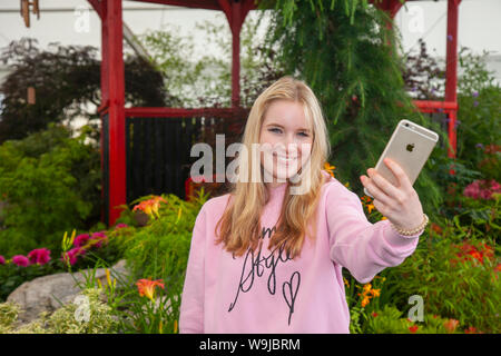 Southport, Merseyside. UK Weather. 14th Aug, 2019. Eva Appleton taking a selfie at J&A Japonicas display; Final touches to exhibits and displays at the 2019 show.  Southport Flower Show is the largest independent flower show in the country. Renowned for its spectacular show gardens and grand floral marquee, and  amateur' growers and floral art competitions. Further bad weather and heavy rain is forecast over the weekend which effect attendance on the occasion of the 90th such event.  Credit: MWI/AlamyLiveNews Stock Photo