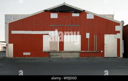 Red warehouse wall with closed gray gates Stock Photo