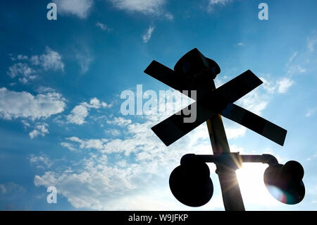 Railroad crossing warning lights silhouette against the sky. Stock Photo