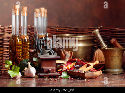 Various vintage cooking utensils with spices, seasonings and bottles of olive oil. Old kitchen utensils on a brown background. Stock Photo