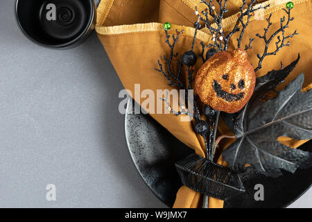 Orange and black place setting with napkin, plate, pumpkin, leaf, and twigs on a dark background with room for text Stock Photo