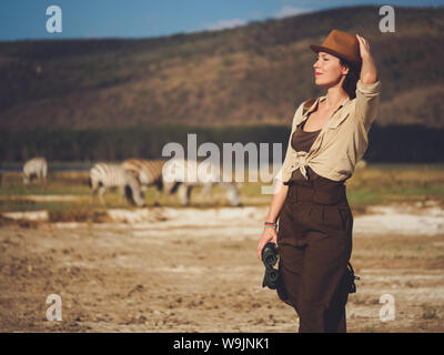 Beautiful woman with binoculars at savanna in Kenya Stock Photo