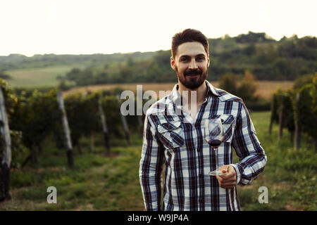 Young handsome man drinking wine in vineyard Stock Photo