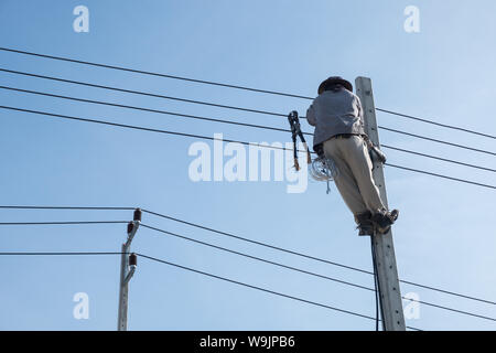 Electricty Power Lines Man Climbing. Repair Man Repair Electrical Installations. Stock Photo