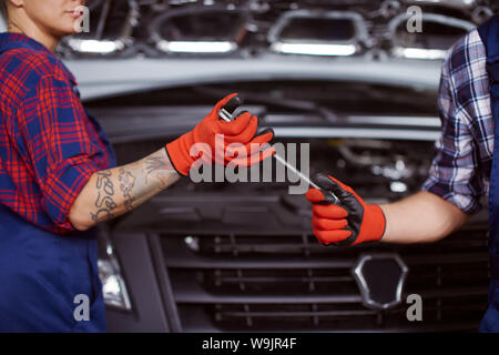 Two mechanics work under repairing a microbus before they get paid for it.. Stock Photo