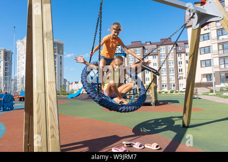 Two girls swinging strongly on a big round swing Stock Photo