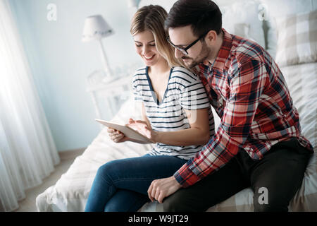 Young happy couple using tablet in bedroom Stock Photo