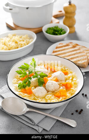 Hot chicken soup, broth with meatballs, carrot, pasta and fresh parsley Stock Photo