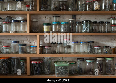 Rows of recycled glass jars containers used to store different sized screws, nails, boats, washers, nuts in an organised manner Stock Photo