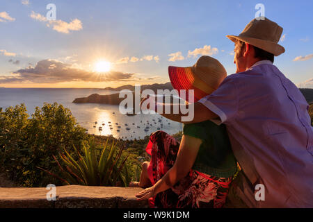 Couple look towards English Harbour from Shirley Heights at sunset, Antigua, Antigua and Barbuda, Leeward Islands, West Indies, Caribbean