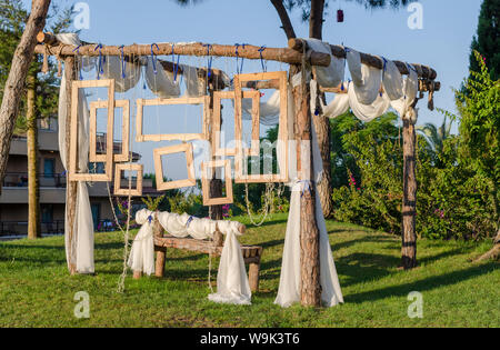 Rustic Wedding Photo booth Set-up outside. Wooden bench with hanging wooden frames as background. Stock Photo