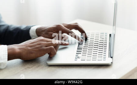 African man typing on laptop keyboard writing business letters Stock Photo