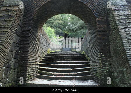 Image of an old stone tunnel arch and stairs in front of trees and a small building in Rivington Pike Stock Photo