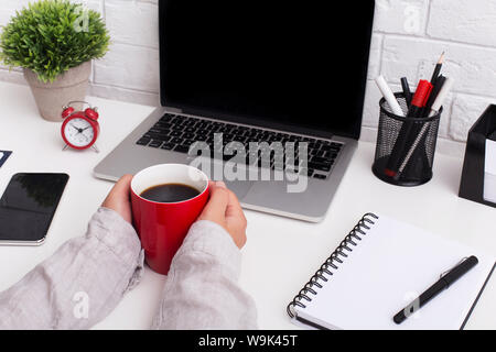 Woman holding red cup with coffee in front of laptop Stock Photo