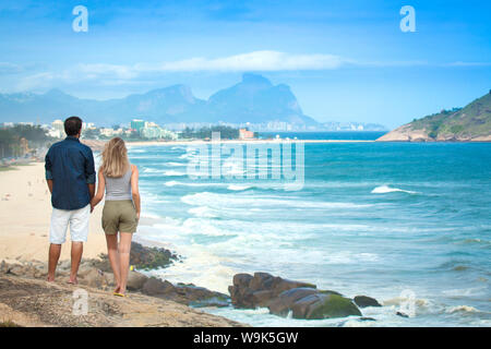 A young couple looking out over Pontal beach, Barra da Tijuca and the Pedra da Gavea, Rio de Janeiro State, Brazil, South America Stock Photo