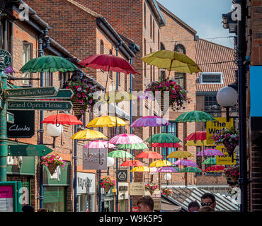 Coloured umbrellas suspended above shoppers in Coppergate shopping centre, York, UK. Stock Photo